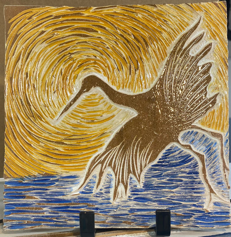 hand made ceramic tile with carved heron behind yellow sun, blue water